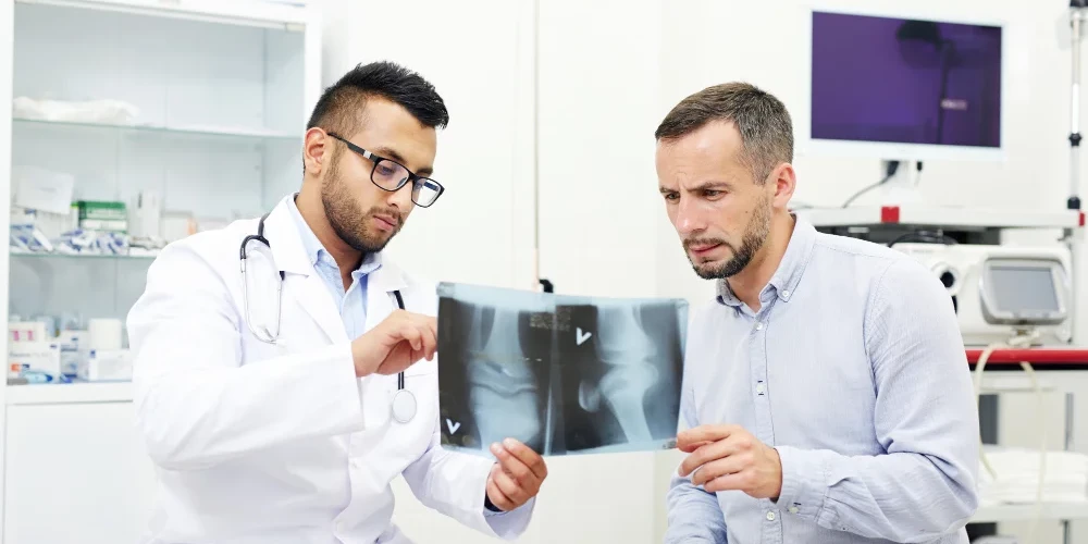 Orthopedic surgeon explaining x ray results to patient