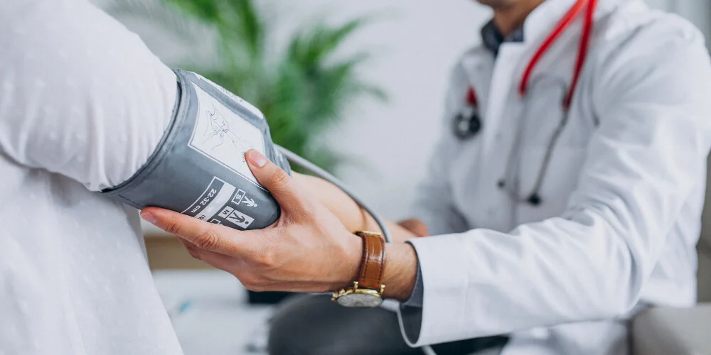 Young male physician with patient measuring blood pressure